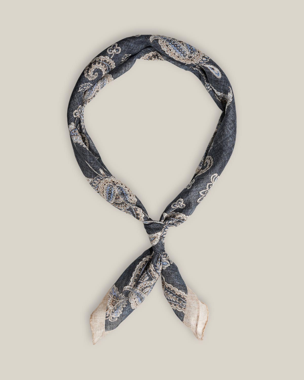 Navy cotton bandana with intricate light paisley motifs and a pale contrasting border, tied as a neck scarf.