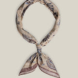 Beige cotton bandana with intricate dark paisley motifs and a muted contrasting border, tied as a neck scarf.