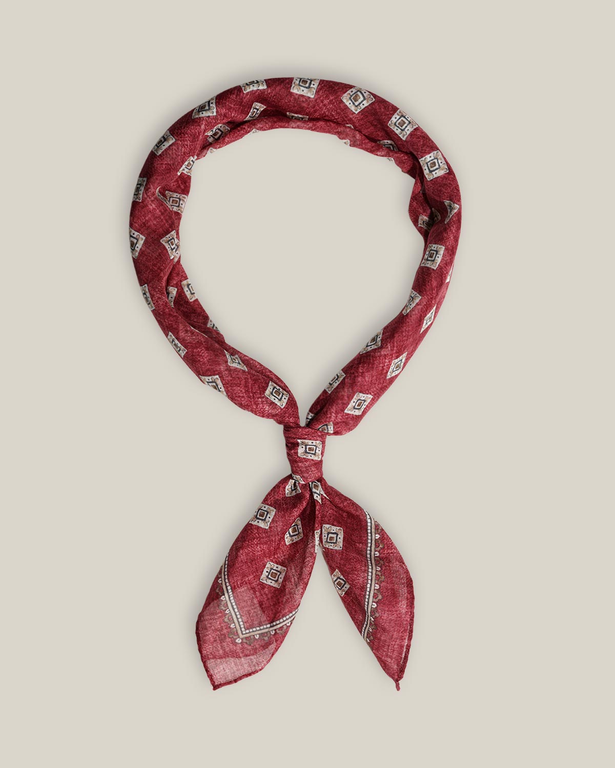 Burgundy cotton bandana with small contrasting geometric motifs and a patterned border, tied as a neck scarf.