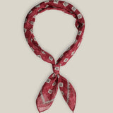 Burgundy cotton bandana with small contrasting geometric motifs and a patterned border, tied as a neck scarf.