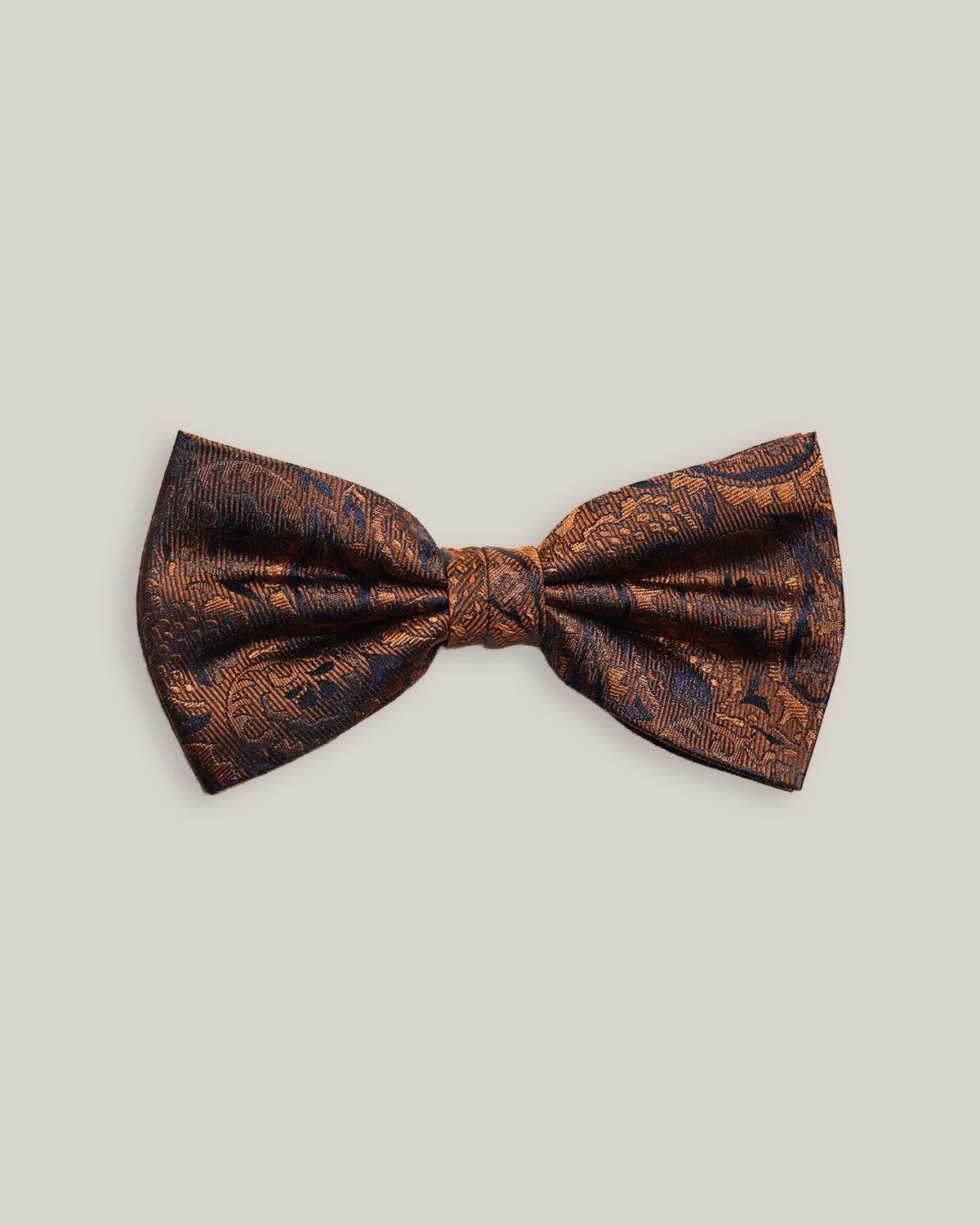 Rust silk bow tie with a dark contrasting woven paisley pattern, front view