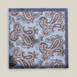 Light-blue printed silk pocket square with large brown, ivory and deep blue paisley motifs and a contrasting navy border.