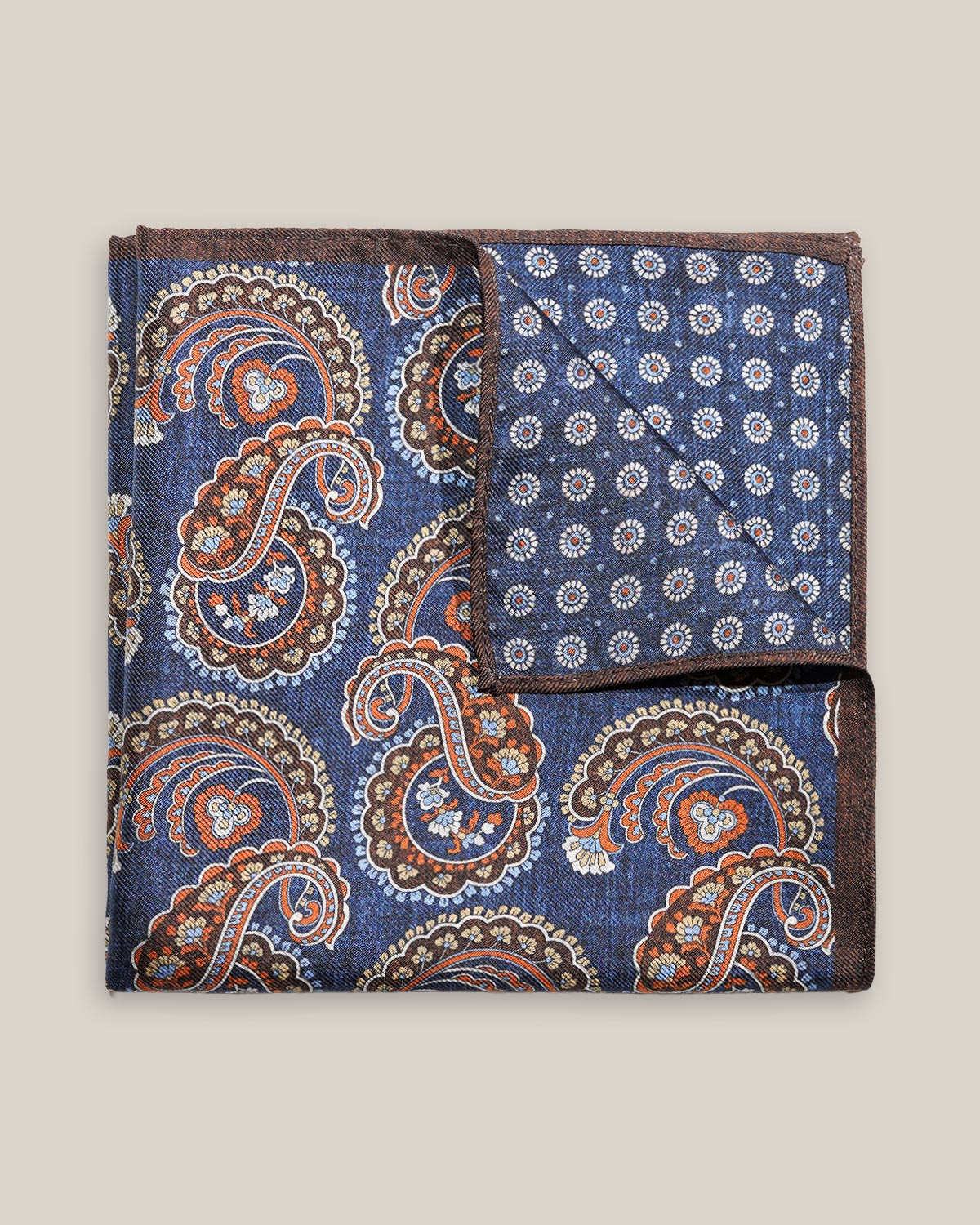Navy double-face silk pocket square with ornate brown, orange and ivory paisley, a small floral medallion reverse and a brown border.