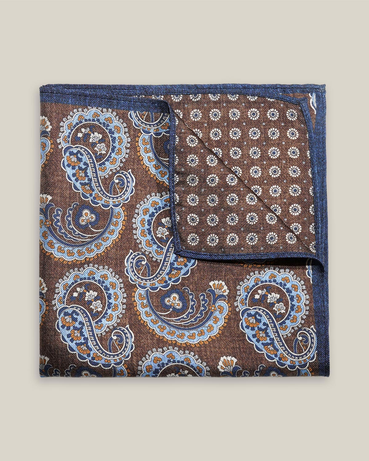 Brown double-face silk pocket square with ornate pale blue, navy, ochre and ivory paisley, a small floral medallion reverse and a navy border.