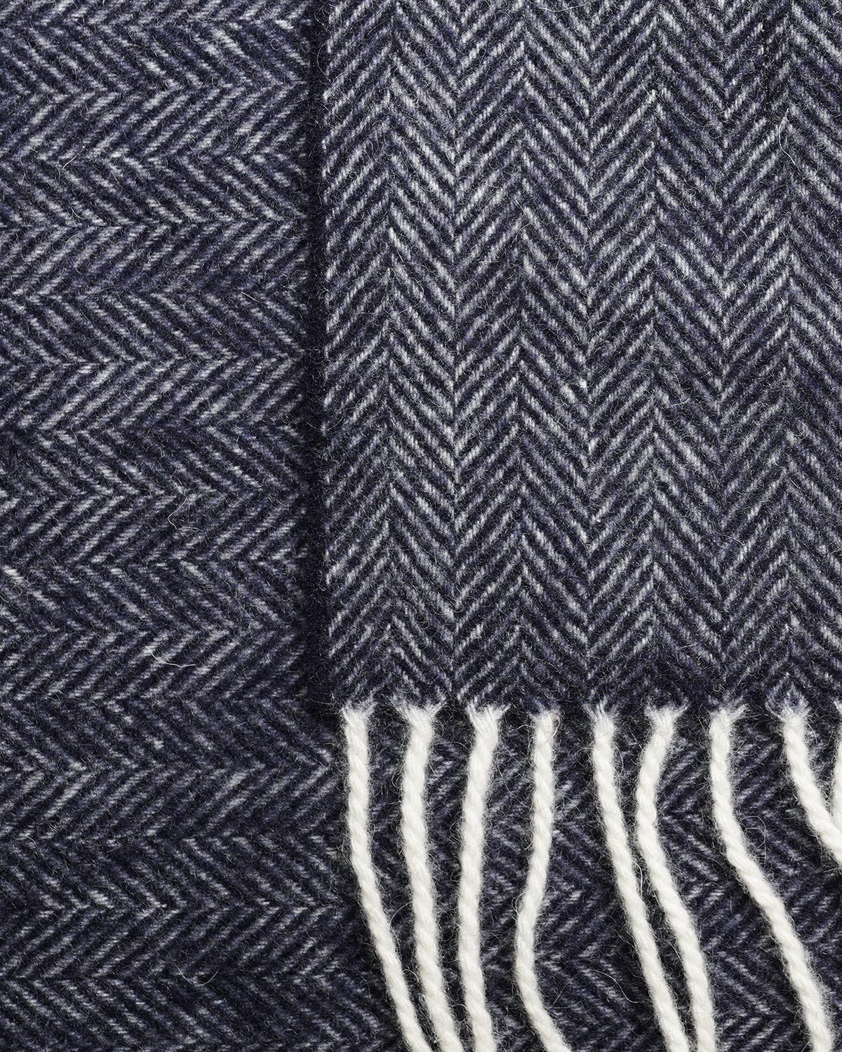 Close-up of the blue and light-toned herringbone weave and light fringes on a pure wool scarf