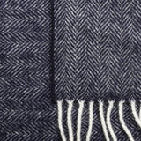 Close-up of the blue and light-toned herringbone weave and light fringes on a pure wool scarf