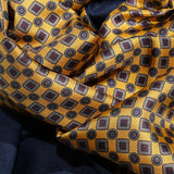 Draped golden geometric printed silk with burgundy accents alongside the scarf's navy wool backing