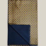 Golden-yellow geometric printed silk scarf folded to show its plain navy wool backing and short fringed edges