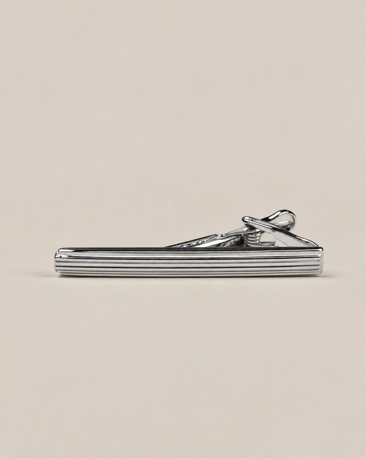 Silver-tone tie clip with fine horizontal grooves and a spring-loaded fastening.