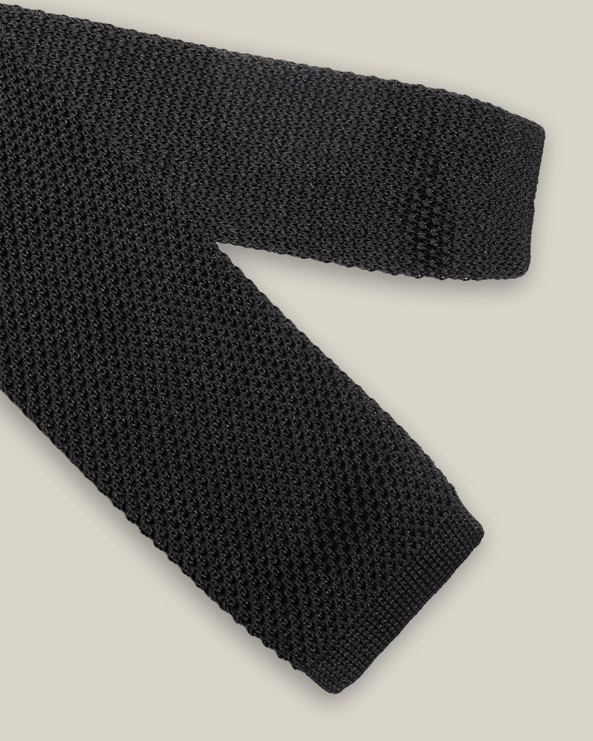 Black knitted tie with a textured surface and classic straight square end