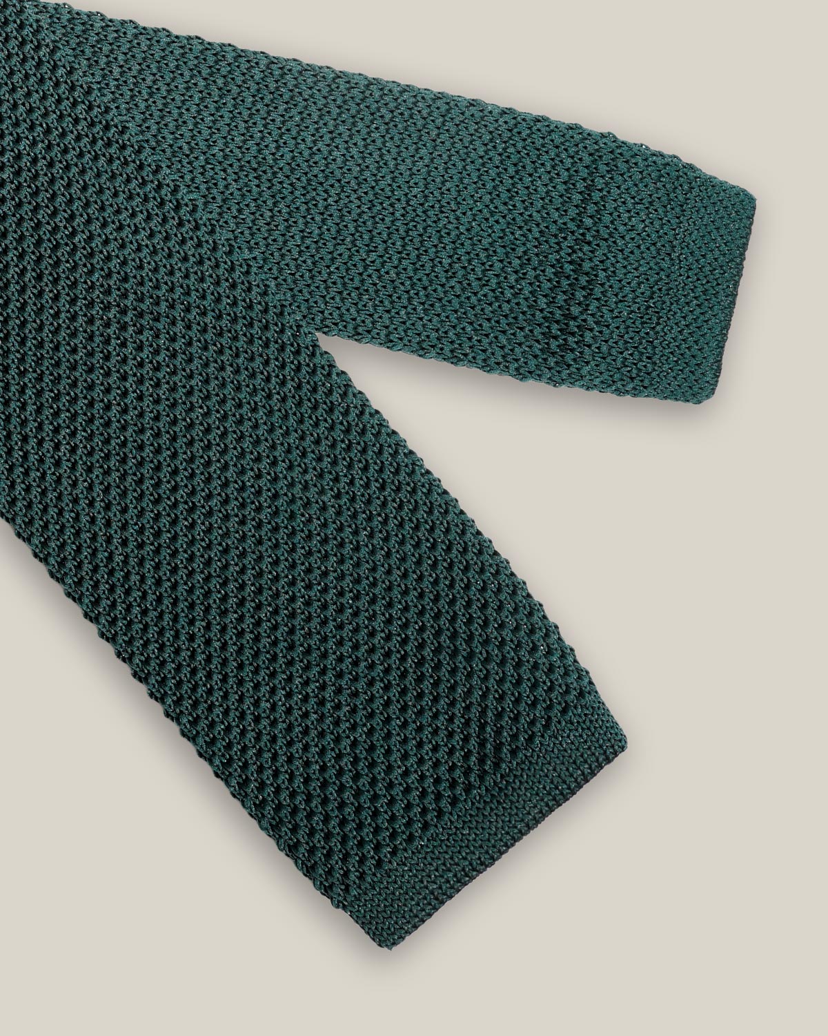 Deep green knitted tie with a textured surface and classic straight square end