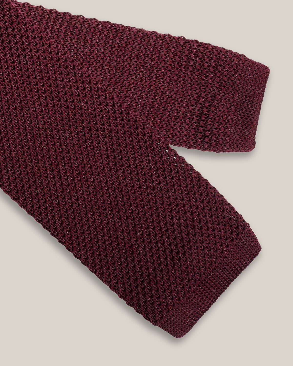 Burgundy knitted tie with a textured surface and classic straight square end