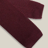 Burgundy knitted tie with a textured surface and classic straight square end