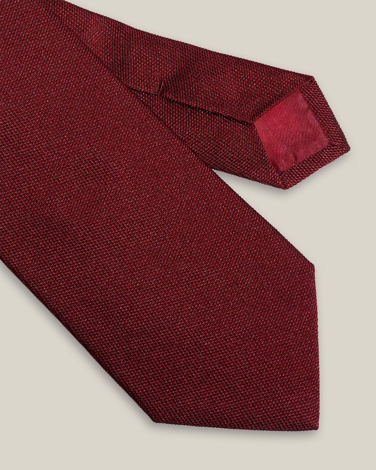Burgundy woven pure silk tie on a neutral background