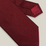 Burgundy woven pure silk tie on a neutral background