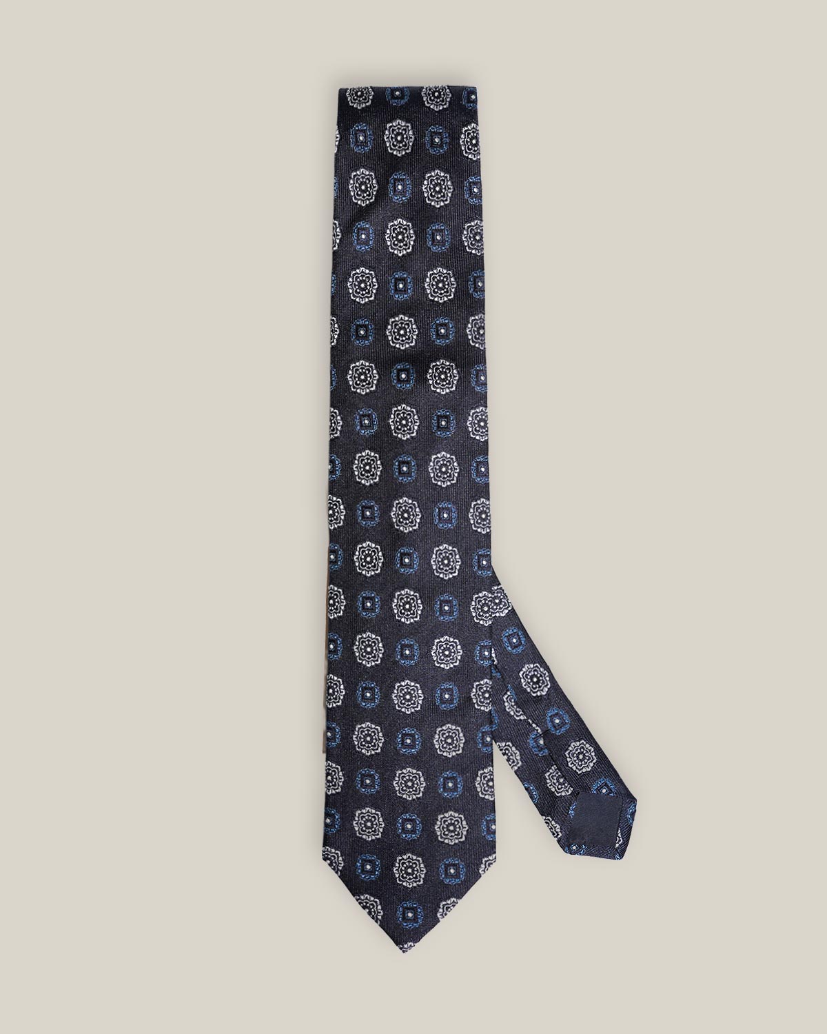 Navy woven silk tie with repeating light blue and silver-toned geometric medallions