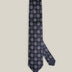 Navy woven silk tie with repeating light blue and silver-toned geometric medallions