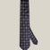 Navy woven silk tie with repeating silver-toned geometric medallions on a light background