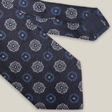 Navy woven silk tie with repeating light blue and silver-toned geometric medallions