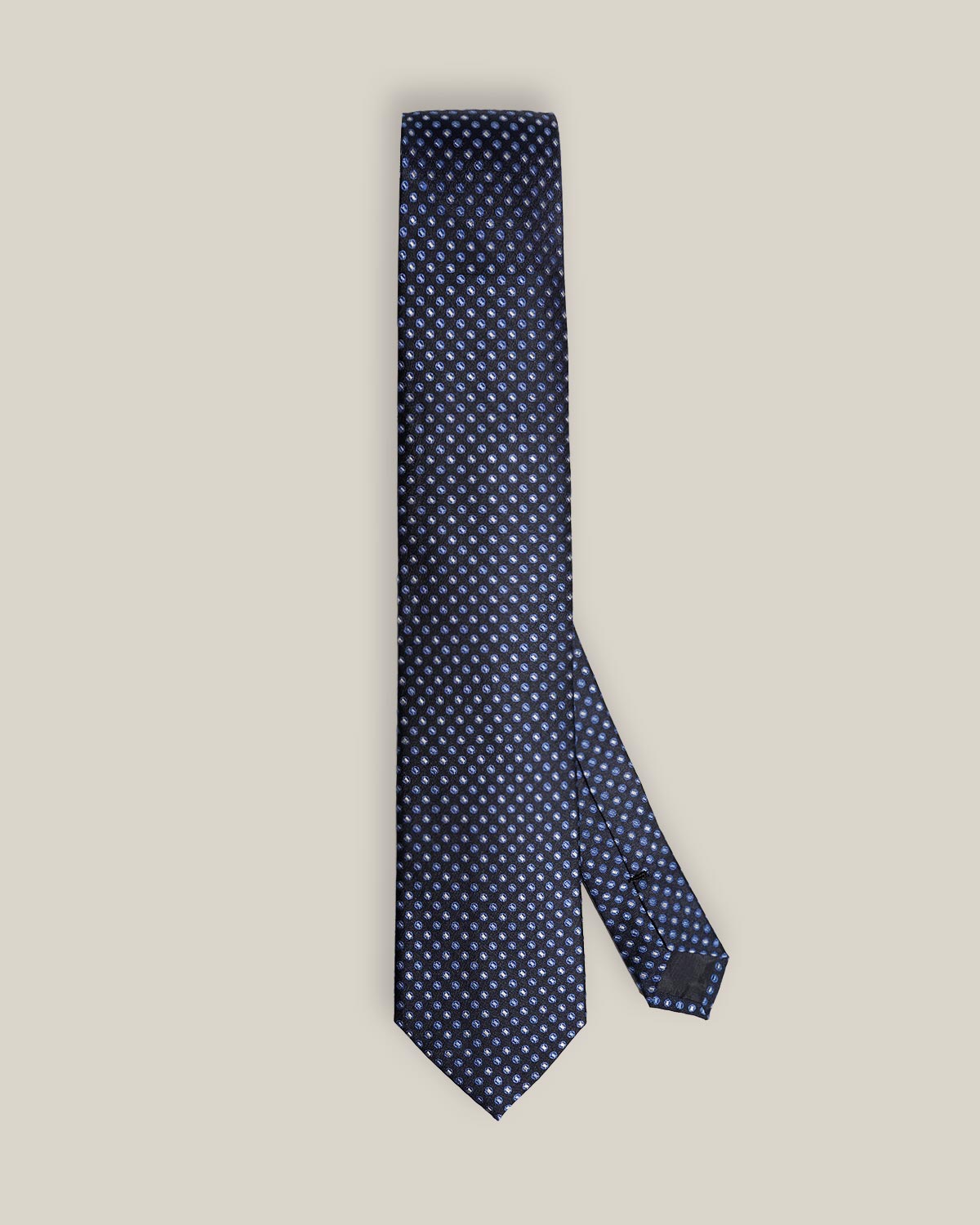 Full view of a navy silk tie with a repeating light blue and ivory medallion pattern.
