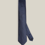 Full view of a navy silk tie with a repeating light blue and ivory medallion pattern.