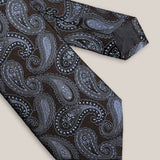 Close-up of light blue and silver paisley motifs on a dark brown 100% silk tie.