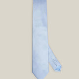 Light blue woven pure silk tie on a neutral background
