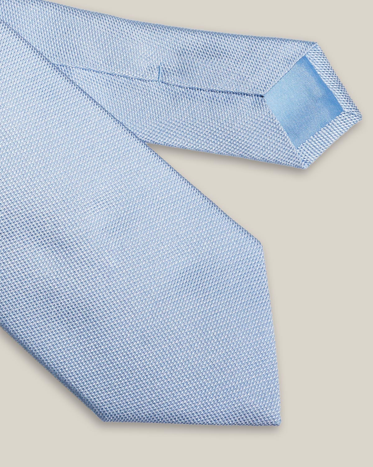 Light blue woven pure silk tie on a neutral background