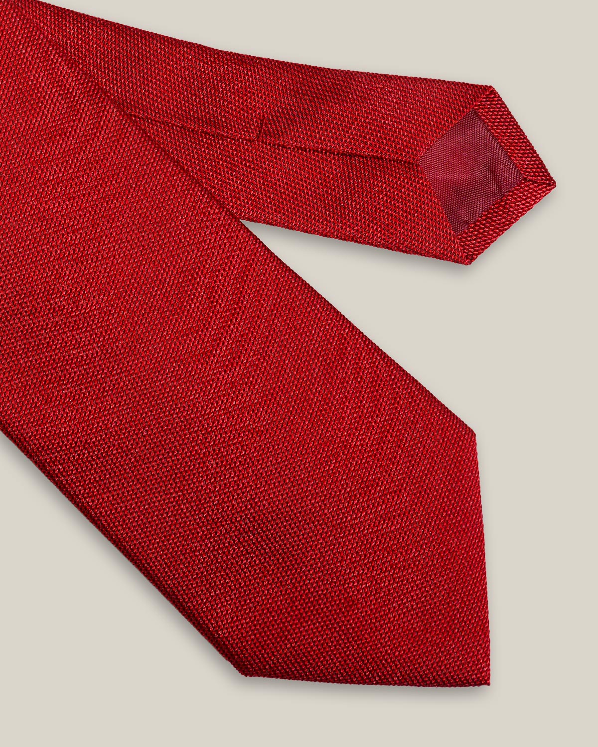 Bright red woven pure silk tie on a neutral background