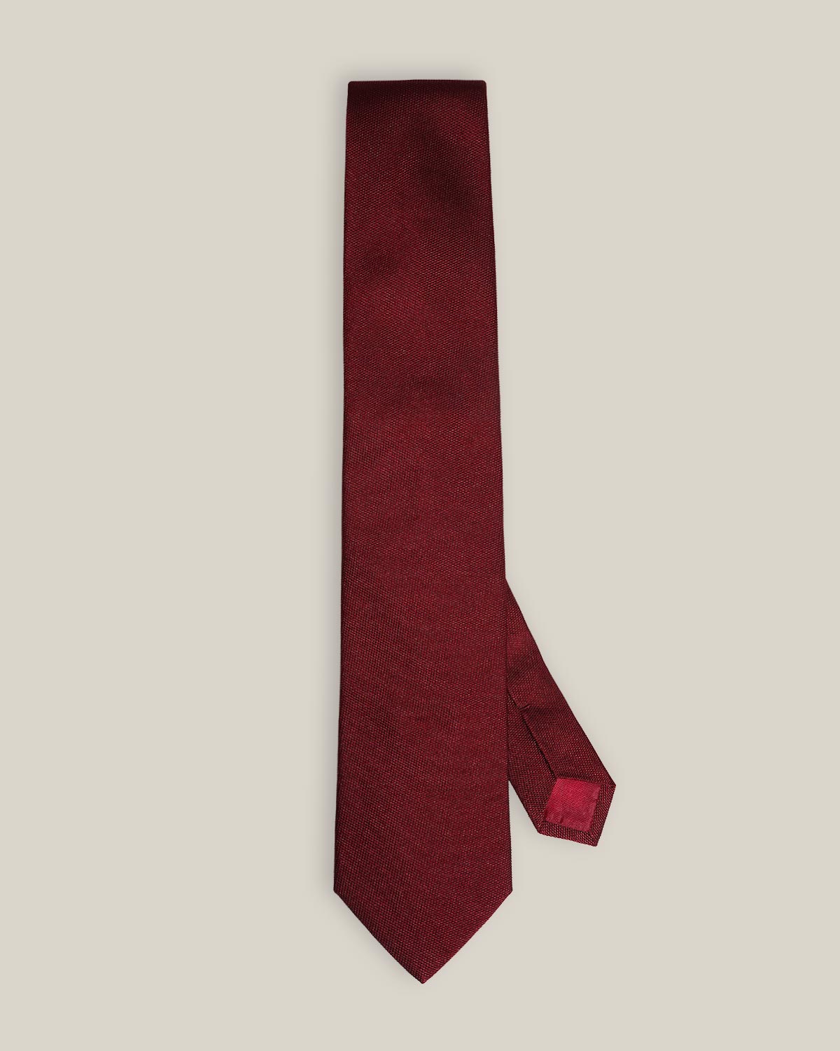 Burgundy woven pure silk tie on a neutral background