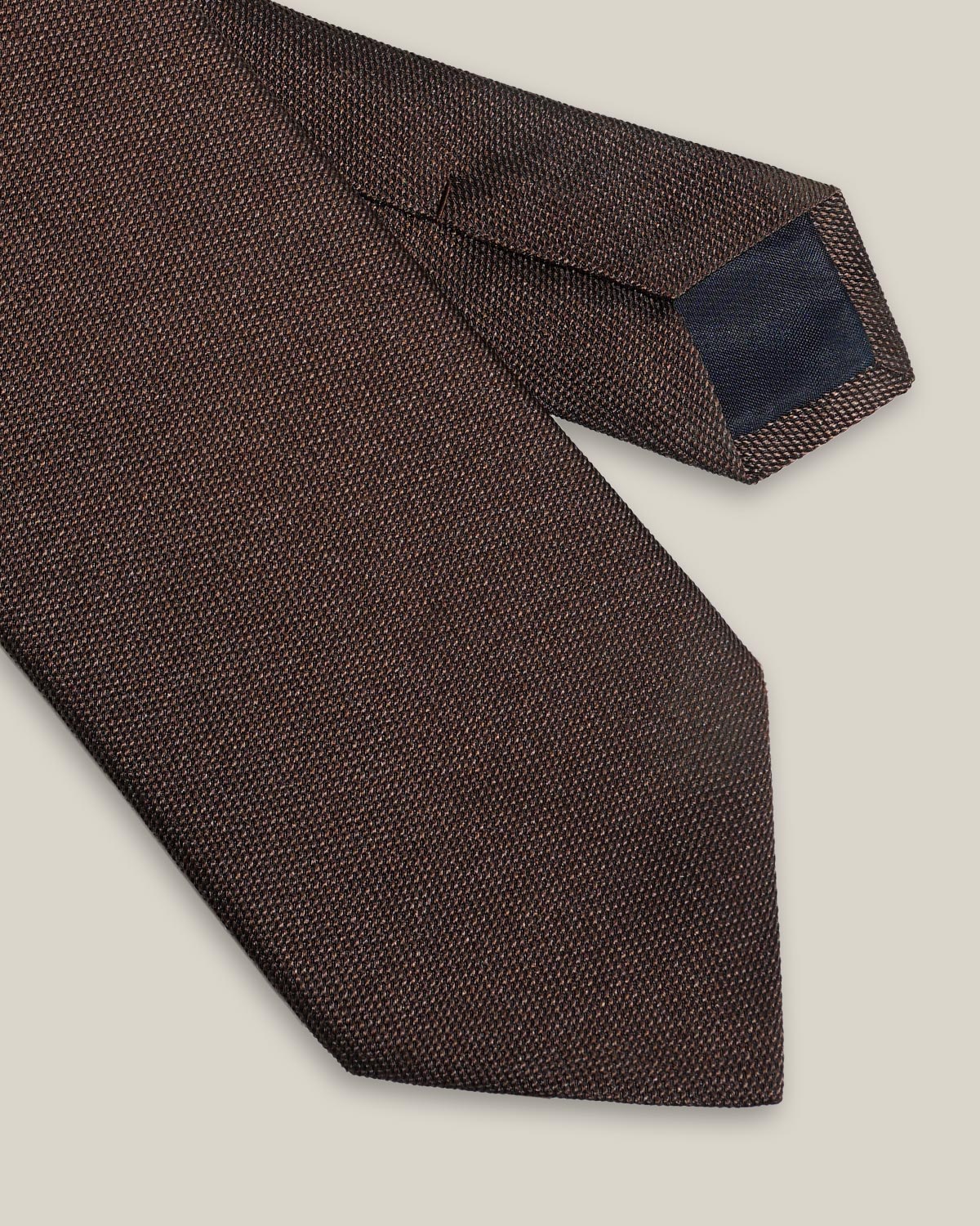Brown woven pure silk tie on a neutral background