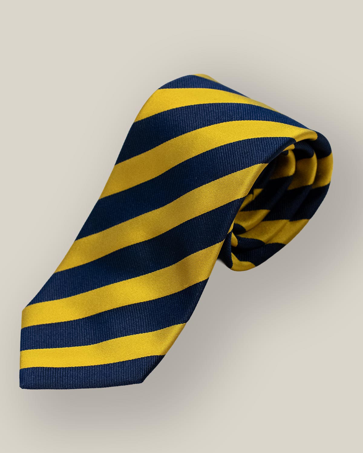 Navy and gold striped silk tie rolled up on neutral background