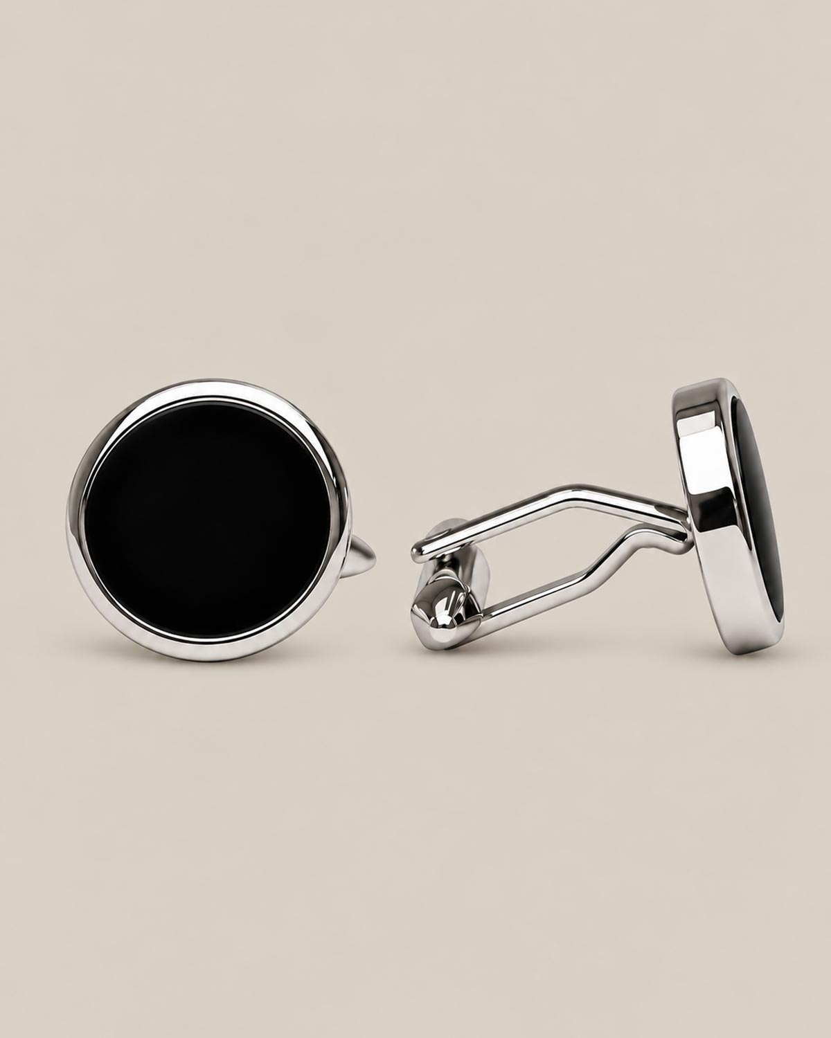 Round silver cufflinks with a deep black onyx face on a beige background