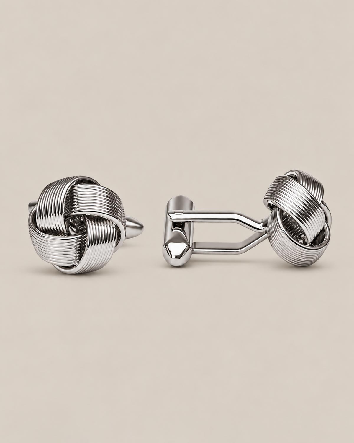 Silver love knot cufflinks in polished woven wire on a beige background